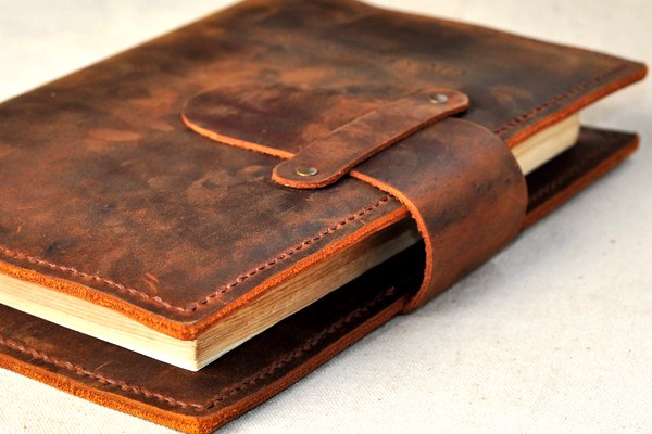 Full-grain leather book cover with snap closure and hand stitching